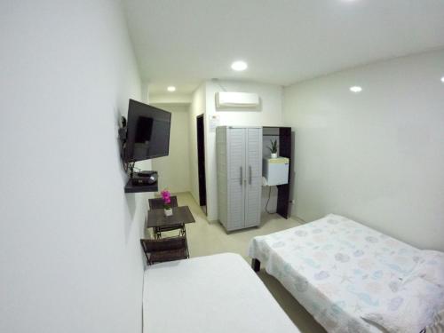 Habitación pequeña con 2 camas y TV. en Hotel Almendros, en San Andrés