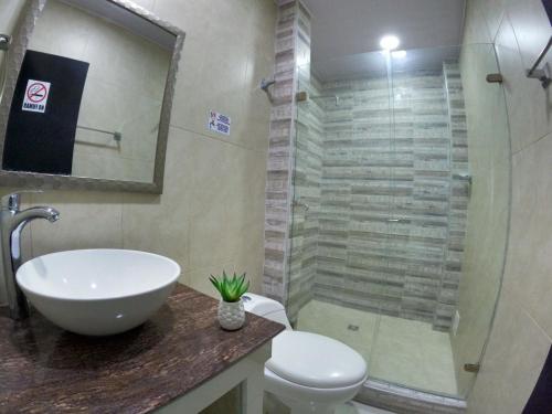 y baño con aseo, lavabo y ducha. en Hotel Almendros en San Andrés