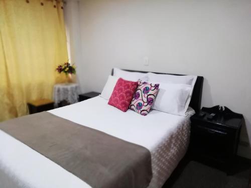 sypialnia z białym łóżkiem i kolorowymi poduszkami w obiekcie Habitaciones en Edificio Ginebra Manizales w mieście La Linda