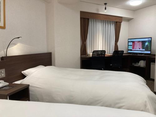 山口市にあるホテルアルファーワン山口インターのベッド、デスク、コンピュータが備わるホテルルームです。