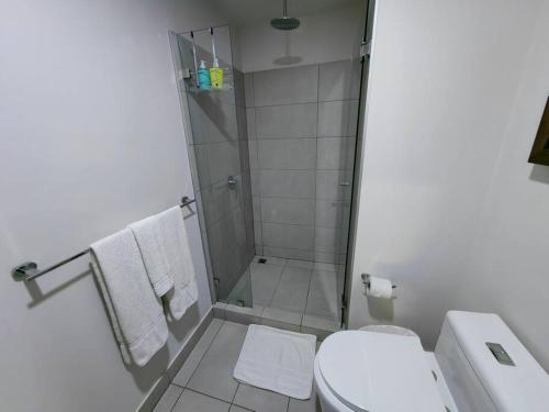 a bathroom with a shower and a toilet with towels at 804 SECRT Sabana Hermoso Apartamento con Aire Acondicionado in San José