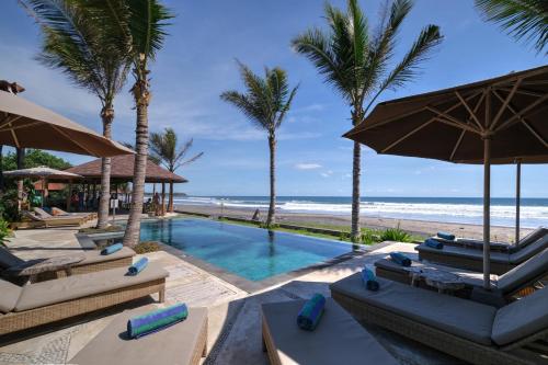 una piscina con sillas y sombrillas junto a la playa en Wide Sands Beach Retreat, en Pulukan