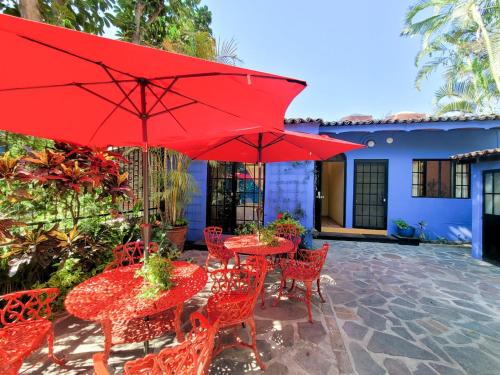 een patio met rode tafels en stoelen met rode parasols bij Estrellita's Bed & Breakfast in Ajijic