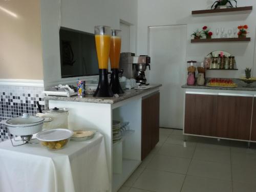 a kitchen with a table with a blender with orange juice at Hotel Pousada Oasis in Conde