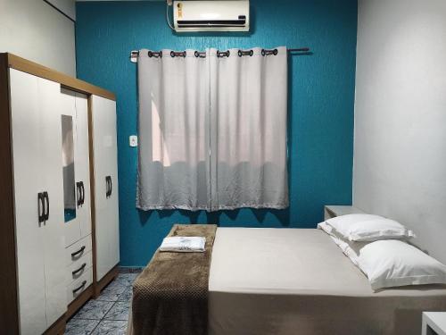 a blue bedroom with a bed and a window at Apartamentos aconchegantes no centro da cidade in Cacoal