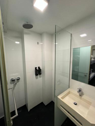 a bathroom with a sink and a shower with a mirror at D'Nova Hotel Bugis in Singapore