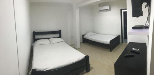 a small bedroom with two beds and a table at Hotel Las Gaviotas in San Andrés
