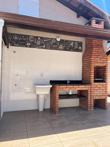 a bathroom with a sink and a brick fireplace at Casa Térrea - Nova Itanhaém in Itanhaém