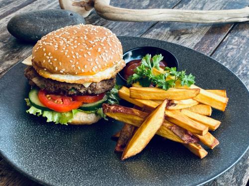 a hamburger and french fries on a black plate at Wide Sands Beach Retreat in Pulukan