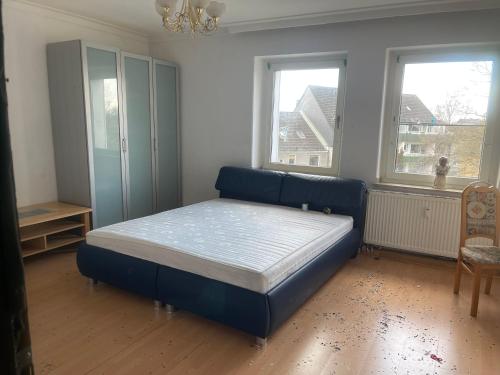a bedroom with a blue bed and two windows at Apartment groß 4 Zimmer in Essen