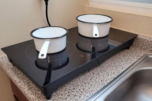 two pots sitting on top of a black counter at Jayuya Cozy Aparment with Wi-Fi, Free Parking and AC in Jayuya