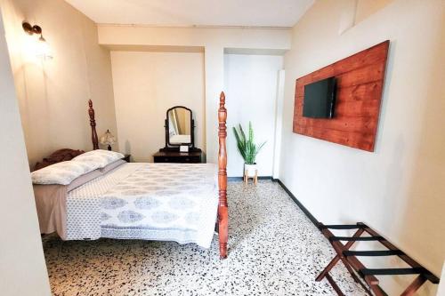 ein Schlafzimmer mit einem Bett und einem Spiegel sowie einem TV in der Unterkunft Jayuya Cozy Aparment with Wi-Fi, Free Parking and AC in Jayuya