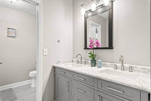 a white bathroom with a sink and a mirror at Renovated 3BR Retreat with Large Patio & Grill in Charlotte