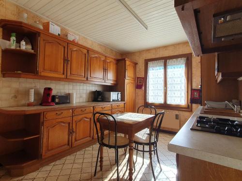une cuisine avec des armoires en bois et une table et des chaises dans l'établissement Maison confortable avec jardin proche plage, 3 chambres, WiFi, animaux sur demande - FR-1-476-135, à LʼAiguillon-sur-Mer