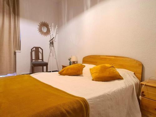 - une chambre avec un lit et 2 oreillers jaunes dans l'établissement Appartement T2 avec balcon au cœur de Collioure, à deux pas de la plage et des commerces - FR-1-309-285, à Collioure