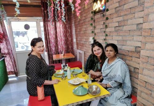 três mulheres sentadas numa mesa num restaurante em Dk's Paradise Homestay em Agra