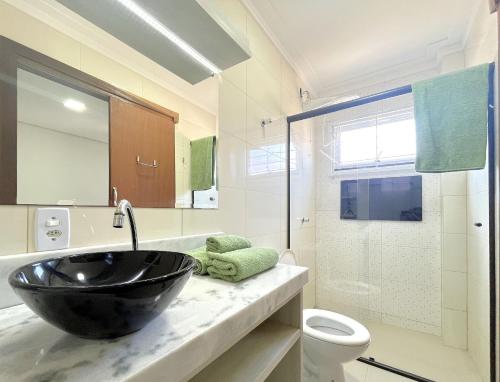 ein Bad mit einem schwarzen Waschbecken und einem WC in der Unterkunft Conforto apenas 250m da praia in Barra Velha