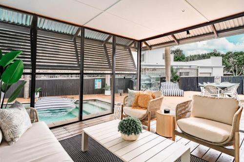 a patio with chairs and a table and a pool at Luxurious Beachside Living in Mudjimba