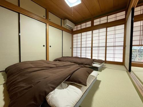 um quarto com três camas num quarto com janelas em 道後の家 em Matsuyama