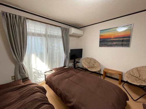 um quarto com uma cama, 2 cadeiras e uma janela em 道後の家 em Matsuyama