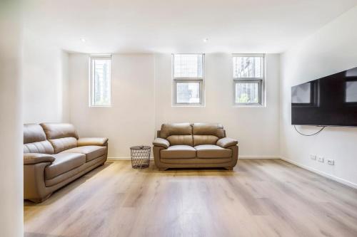 a living room with two couches and a flat screen tv at 2-Bedroom Apartment in Melbourne City with carpark in Melbourne