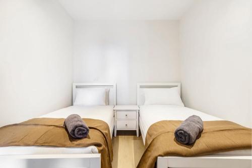 two twin beds in a room with white walls at 2-Bedroom Apartment in Melbourne City with carpark in Melbourne