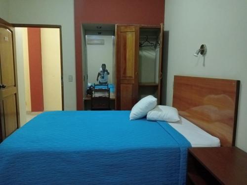 Un dormitorio con una cama azul y una persona en un espejo en Hotel Las Palmeras Iquitos, en Iquitos