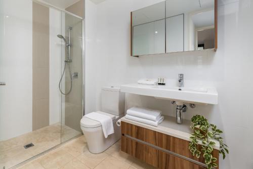 a bathroom with a toilet and a sink and a shower at Spacious 1-Bed with View in Central Location in Canberra