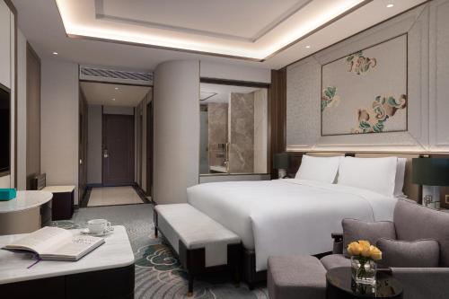 a bedroom with a large white bed and a desk at Sofitel Xiong An in Baoding