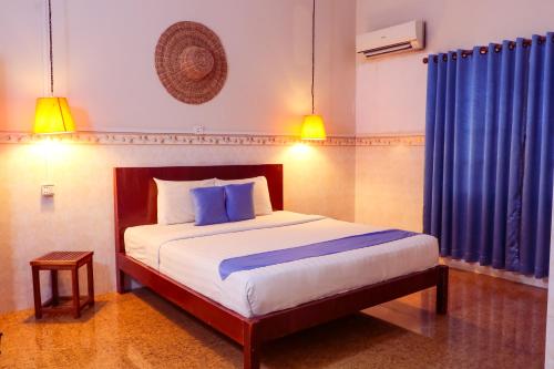 a bedroom with a large bed with blue curtains at Le Tonle in Kratie