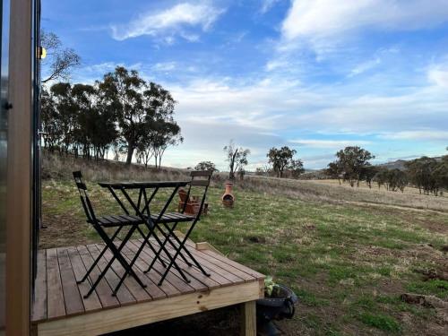 a chair sitting on a wooden deck in a field at Willow Three Tiny House in Willow Tree