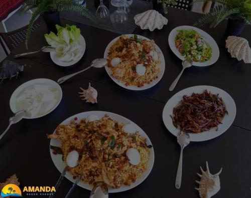 una mesa cubierta con platos de comida y cucharas en Amanda Beach Resort en Pasikuda