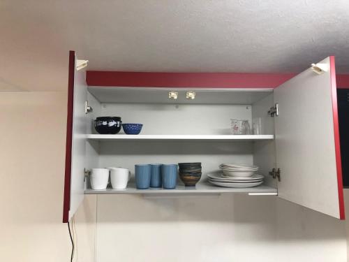 a cupboard with plates and bowls in it at Apartment Heights HANA in Sakai