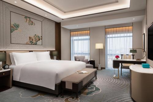 ein Hotelzimmer mit einem großen Bett und einem Schreibtisch in der Unterkunft Sofitel Xiong An in Baoding