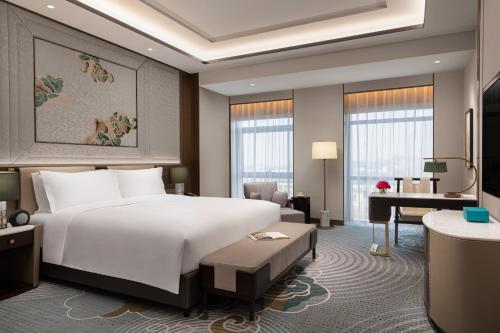 BaodingにあるSofitel Xiong Anの大きなベッドとデスクが備わるホテルルームです。