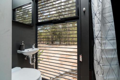 a bathroom with a window with a toilet and a sink at Tiny House 888 in Pokolbin