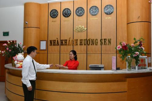 a man and a woman standing at a reception desk at Nhà Khách Hương Sen in Hai Phong