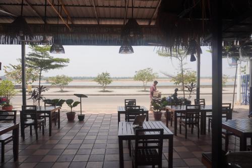 a man standing in a restaurant with tables and chairs at Le Tonle in Kratie