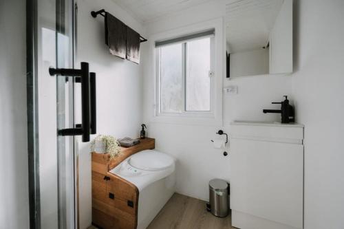 a white bathroom with a toilet and a window at The Big Wollombi Wanderer in Wollombi