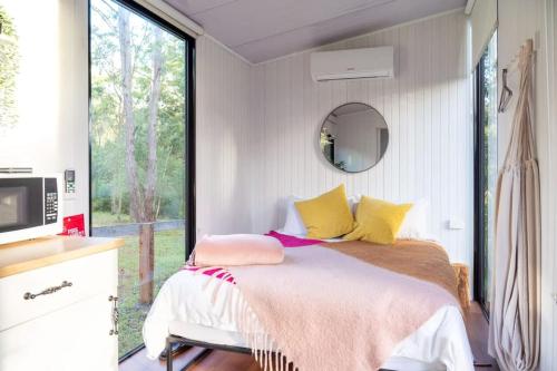 um quarto com uma cama com almofadas amarelas e rosas em Kawal Tiny House em Wollombi