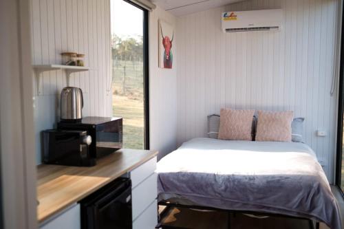 um pequeno quarto com uma cama e um micro-ondas em Maggie's Farmstay em Howes Valley