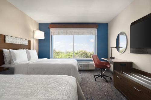 a hotel room with two beds and a window at Holiday Inn Express Cape Canaveral by IHG in Cape Canaveral