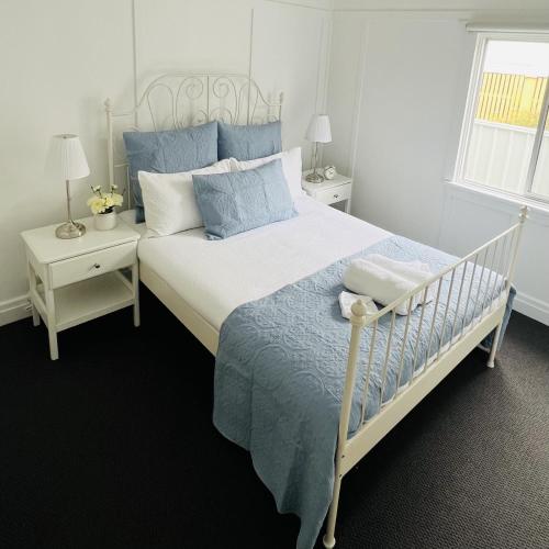 a bedroom with a white bed with blue pillows at Savina Cottage in Stanthorpe