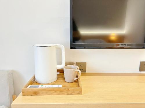 uma mesa com duas canecas de café e uma televisão em Hemu House em Fenghuang