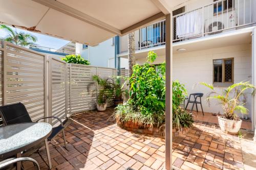 a patio with a table and chairs and plants at Driftwood on the Beach in Yeppoon