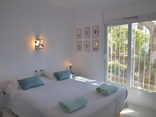 um quarto branco com uma cama grande e almofadas azuis em Apartamento L'Estartit, 3 dormitorios, 6 personas - ES-323-68 em L'Estartit