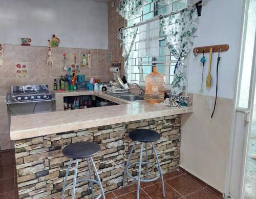 a kitchen with two bar stools at a counter at La casa del descanso in Catemaco