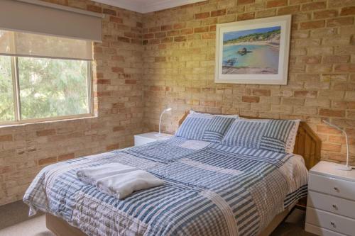 a bedroom with a blue and white bed and a window at Spring Bay Villas, Denmark, WA in Denmark