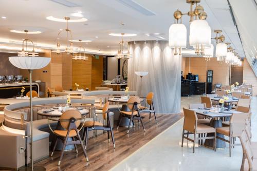 a dining room with tables and chairs and chandeliers at Grand ParcVue Hotel Residence Chengdu in Chengdu