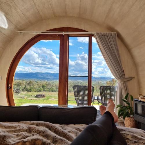 a person laying on a couch looking out a large window at Barrel View Luxury Cabins in Ballandean